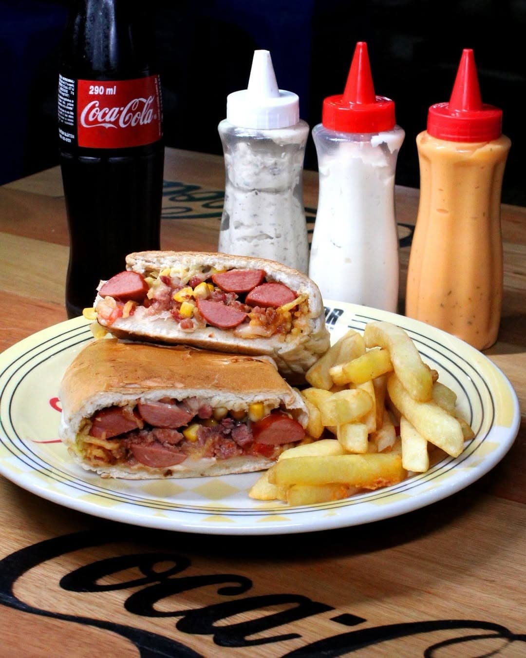 Lanche com fritas, refrigerante e os molhos da mesa