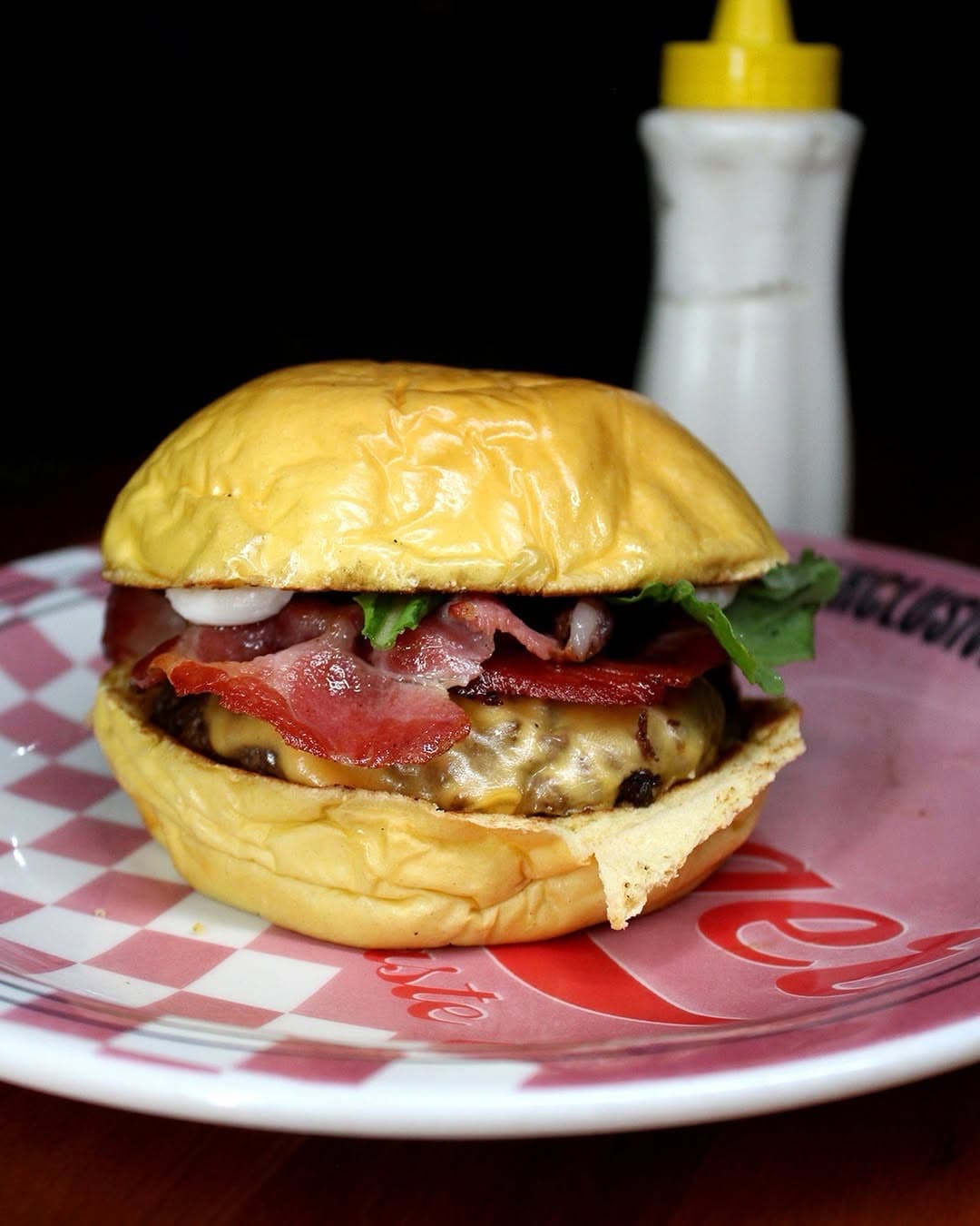 Hambúrguer com bacon e salada num prato xadrez